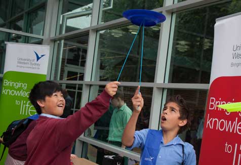 Students balance plates on a stick