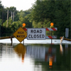 A flooded road with the signs "High Water" and "Road Closed"