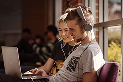 Two students looking at a computer screen with headphones