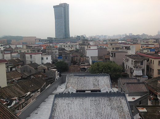 Looking out over rooftops in Zhongshan. Amongst the small dwellings stands one tall building.