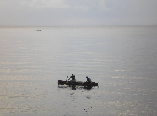 Two men sit in a small boat in the water.