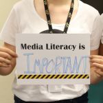 Hands hold a worksheet which has been completed to read ‘Media Literacy is Important’.