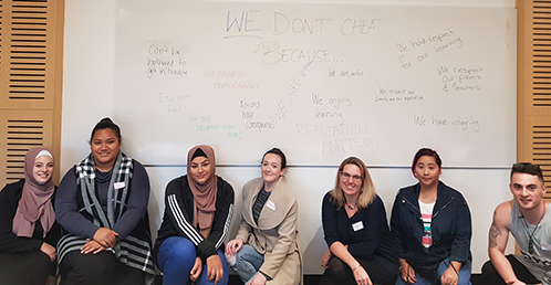 Student Honour code group: seven students, both male and female, from different ethnic backgrounds, sitting in front of a whiteboard.