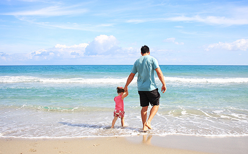 Dad and daughter walking on the beach