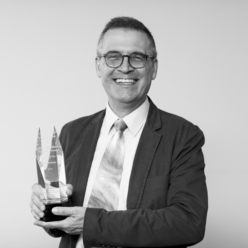 Black and white photo of Professor David Rowe holding his award (glass, engraved)