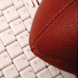 A brown rugby ball sitting on top of a white keyboard.