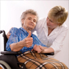 Health care worker and elderly woman in wheelchair giving the thumb-up sign