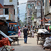 Thumbnail image of a young man walking through a street in a slum 