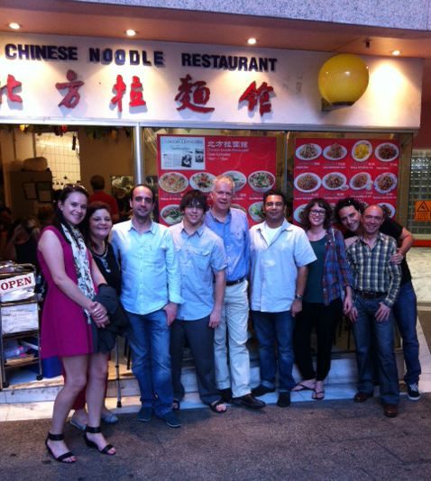A group of nine people, including James Arvanitakis, stand in front of a Chinese Noodle Restaurant.
