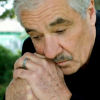 Senior man looking down, feeling dispair, in deep thought, difficulties as husband or father. Showing silver wedding band.
